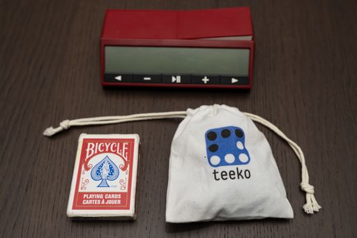 Teeko in its case, near a deck of cards and a chess clock